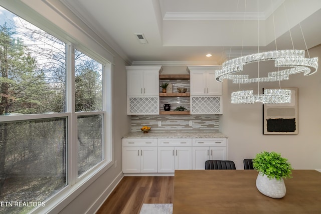 bar featuring light stone counters, ornamental molding, tasteful backsplash, and white cabinets