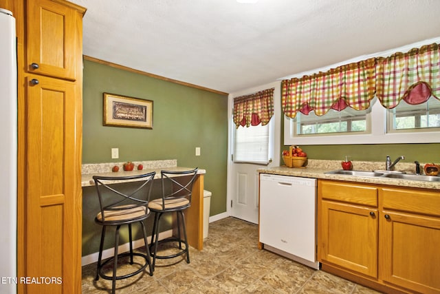 kitchen featuring light tile flooring, sink, a wealth of natural light, and white dishwasher