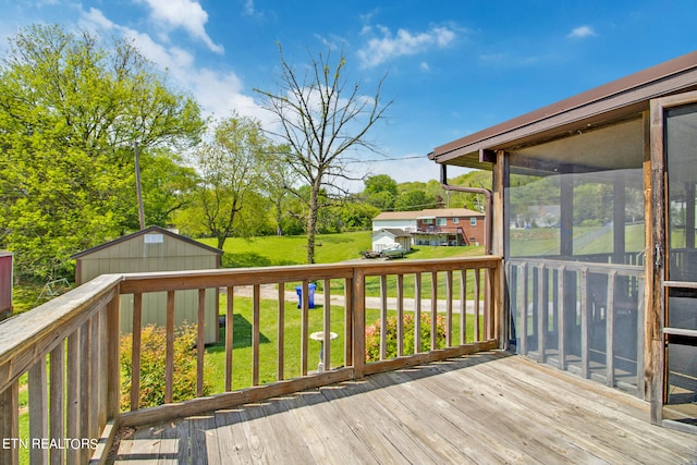 wooden deck featuring a sunroom, a shed, and a lawn