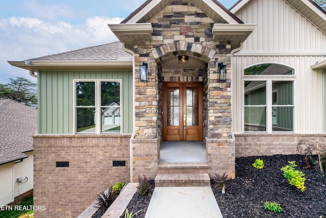 view of exterior entry with roof with shingles, crawl space, stone siding, and board and batten siding