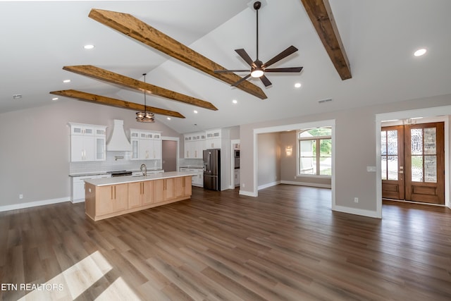 kitchen featuring vaulted ceiling with beams, stainless steel refrigerator with ice dispenser, a spacious island, white cabinetry, and decorative light fixtures