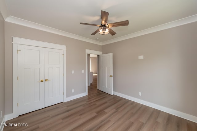 unfurnished bedroom with wood-type flooring, a closet, ceiling fan, and ornamental molding