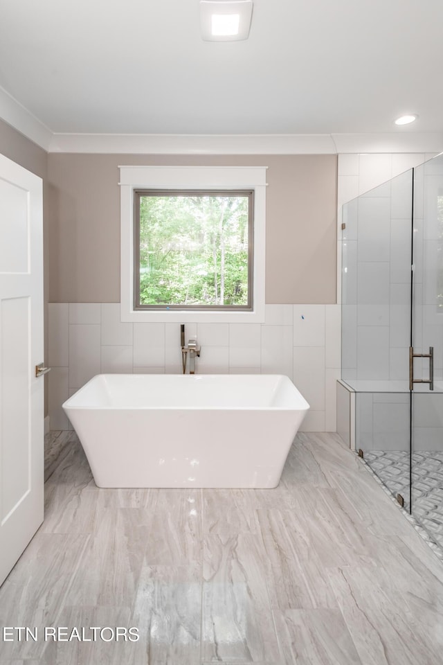 bathroom with tile walls, crown molding, and independent shower and bath