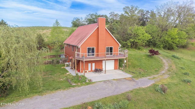 exterior space with a wooden deck, a garage, and a front lawn