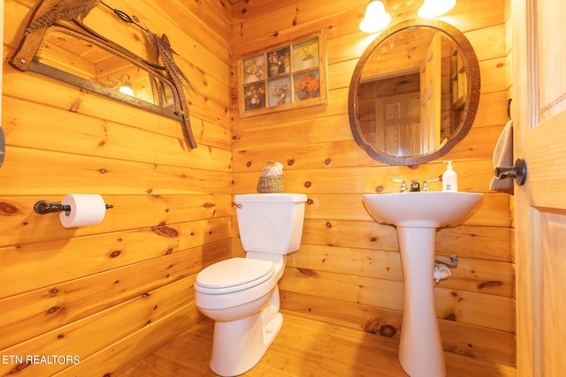 bathroom featuring wooden walls, toilet, and hardwood / wood-style floors