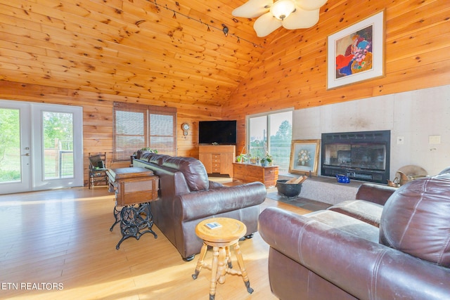 living room featuring wood walls, high vaulted ceiling, wooden ceiling, light hardwood / wood-style floors, and ceiling fan