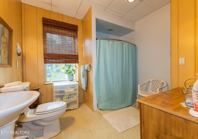 bathroom with wooden walls, toilet, and a paneled ceiling