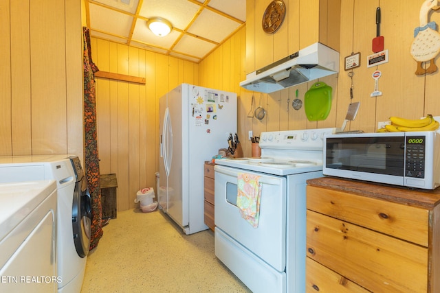 kitchen with white appliances, washer and dryer, and wood walls