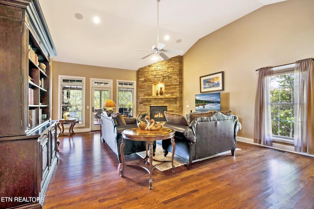 living room featuring high vaulted ceiling, dark hardwood / wood-style flooring, ceiling fan, and a stone fireplace