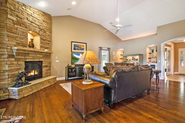 living room with lofted ceiling, ceiling fan, a stone fireplace, and hardwood / wood-style flooring