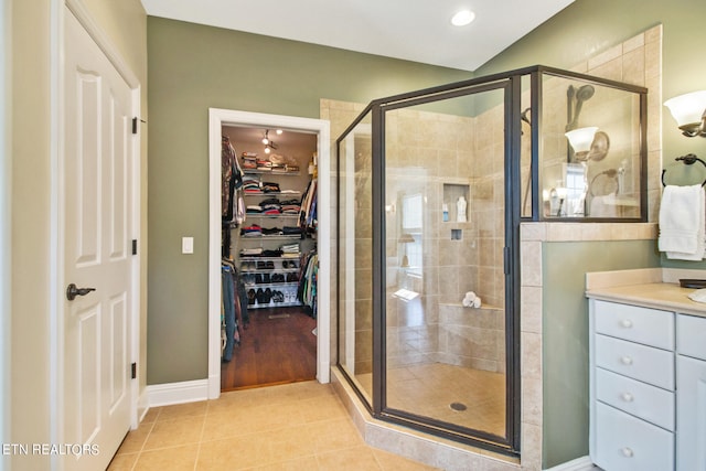 bathroom with walk in shower, tile floors, and vanity