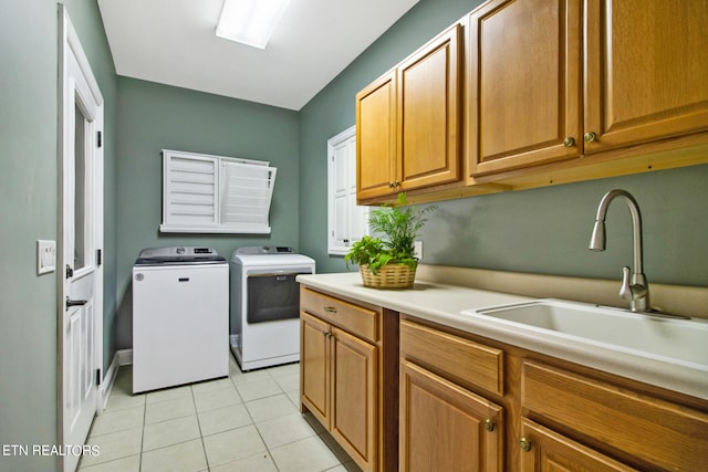 laundry area with cabinets, light tile floors, sink, and washer and clothes dryer