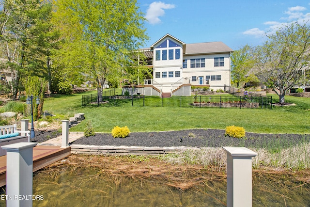 back of property with a water view and a lawn