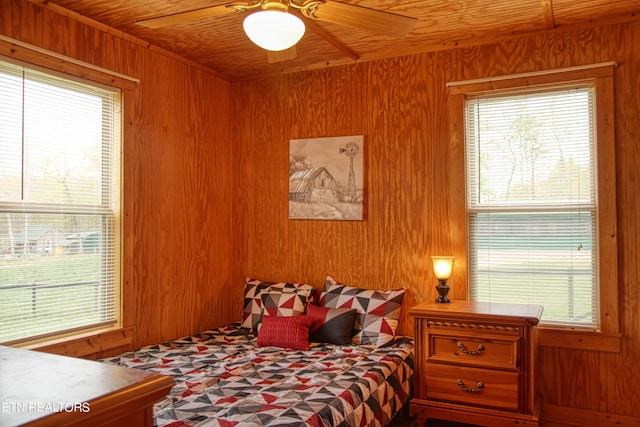 bedroom featuring wood ceiling, wood walls, ceiling fan, and multiple windows