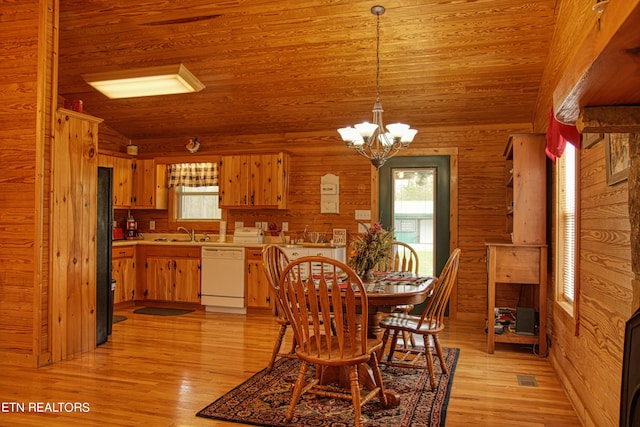 dining space with vaulted ceiling, light hardwood / wood-style flooring, a chandelier, and wood walls