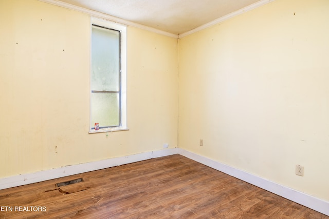 empty room with hardwood / wood-style flooring and ornamental molding