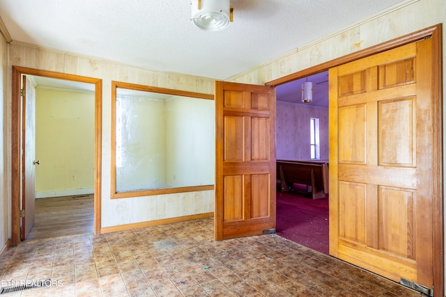 tiled empty room featuring a textured ceiling and ornamental molding