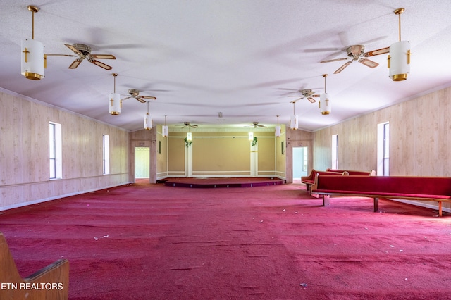 misc room with wood walls, ceiling fan, a textured ceiling, and lofted ceiling