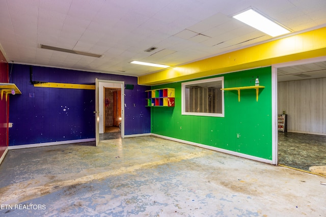 spare room featuring wooden walls and concrete floors