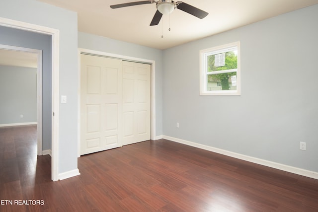 unfurnished bedroom with a closet, dark hardwood / wood-style floors, and ceiling fan