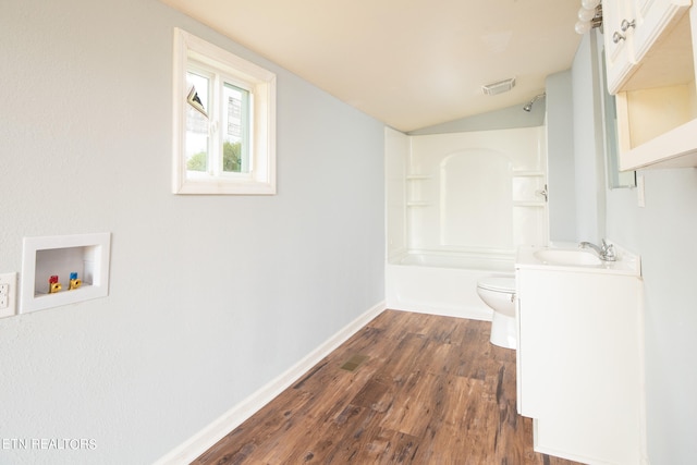 interior space featuring shower / tub combination, vanity, hardwood / wood-style floors, vaulted ceiling, and toilet