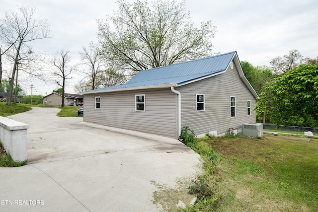 view of side of property with central AC unit and a yard