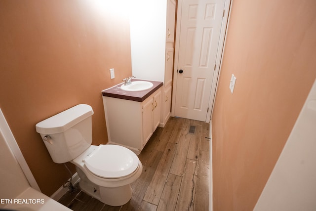 bathroom with wood-type flooring, vanity, and toilet