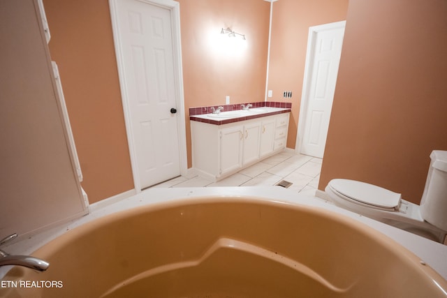 bathroom with a tub, vanity, tile floors, and toilet