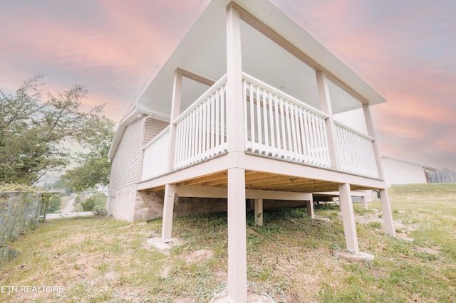 view of side of property with a deck and a lawn