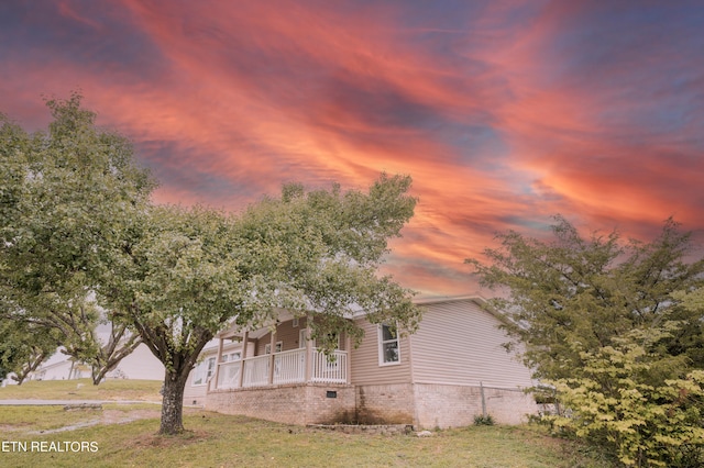 view of front of property featuring covered porch and a yard