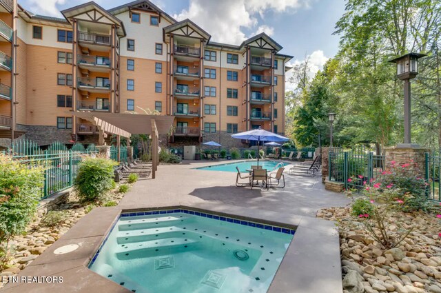 view of pool with a hot tub and a patio