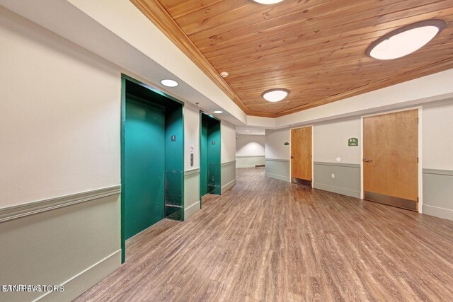 hallway featuring wooden ceiling, light hardwood / wood-style flooring, elevator, and ornamental molding