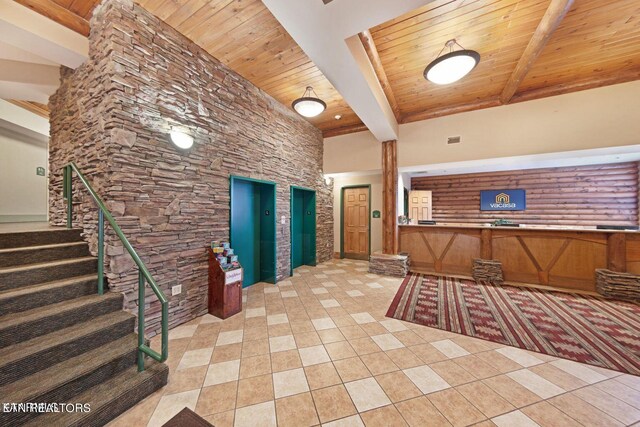 interior space with a towering ceiling, beamed ceiling, wooden ceiling, and light tile flooring