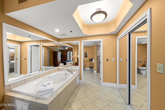 bathroom with sink, tile floors, a raised ceiling, and tiled bath