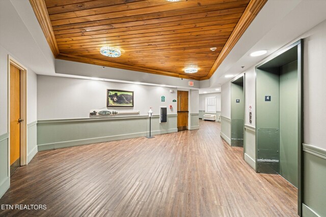 spare room featuring wood ceiling, hardwood / wood-style floors, a tray ceiling, and elevator