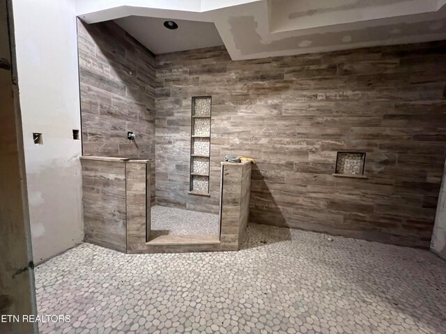 bathroom with a tile shower and tile flooring