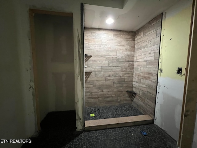 bathroom with a tile shower and tile flooring