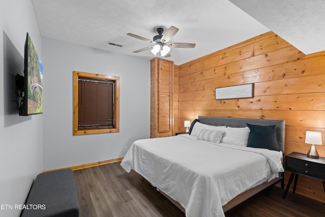 bedroom featuring wood walls, ceiling fan, and dark hardwood / wood-style floors