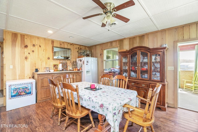 dining area featuring hardwood / wood-style flooring, wood walls, and ceiling fan