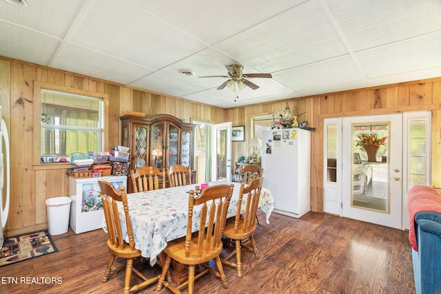 dining room featuring ceiling fan, wooden walls, and dark hardwood / wood-style floors