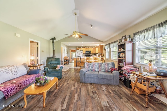 living room featuring hardwood / wood-style floors, vaulted ceiling, ceiling fan, and a wood stove