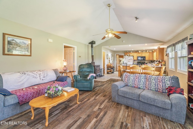 living room with ceiling fan, a wood stove, vaulted ceiling, and hardwood / wood-style flooring