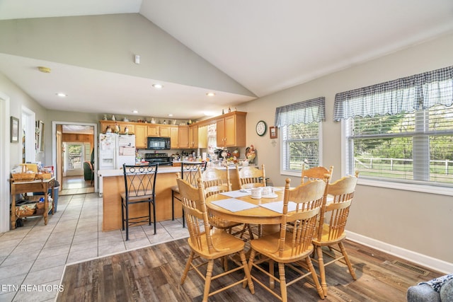 tiled dining space featuring high vaulted ceiling