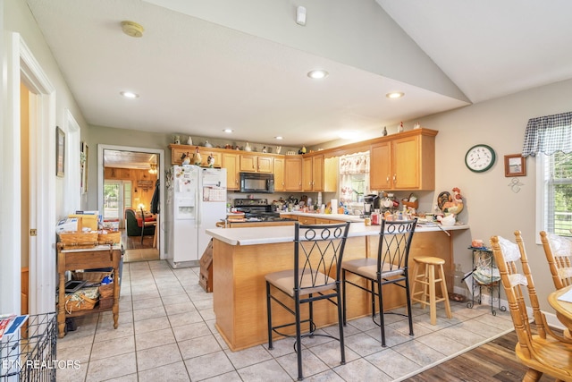 kitchen with white fridge with ice dispenser, kitchen peninsula, electric stove, and light tile flooring