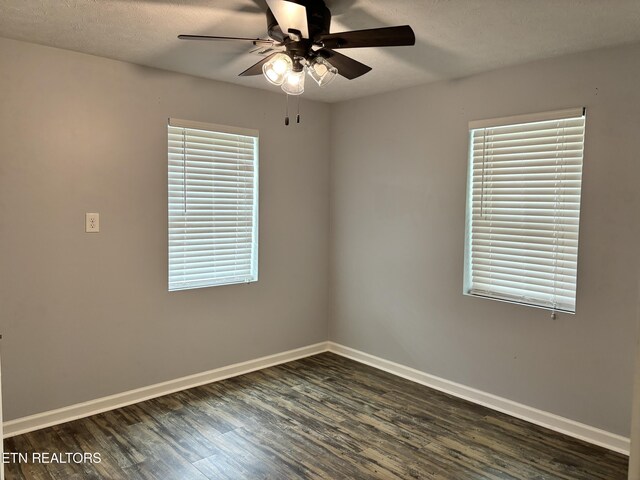 spare room featuring a healthy amount of sunlight, ceiling fan, dark wood-type flooring, and a textured ceiling