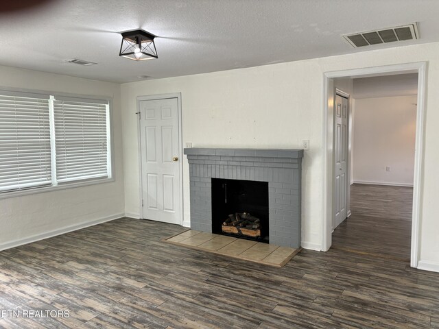 unfurnished living room with a textured ceiling, dark hardwood / wood-style floors, and a brick fireplace