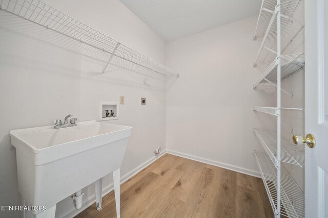 laundry area featuring sink, light hardwood / wood-style floors, electric dryer hookup, and hookup for a washing machine