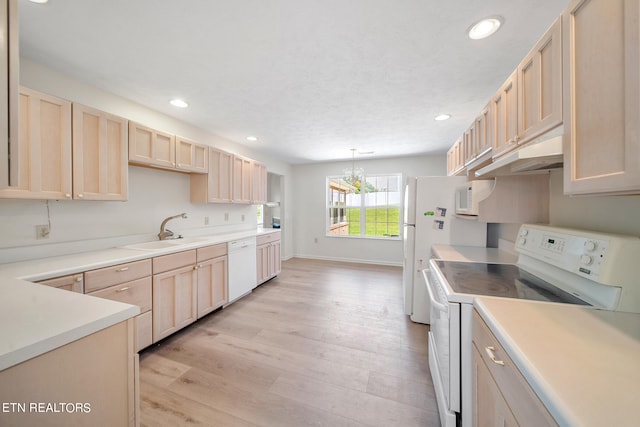 kitchen featuring decorative light fixtures, white appliances, light brown cabinetry, sink, and light wood-type flooring