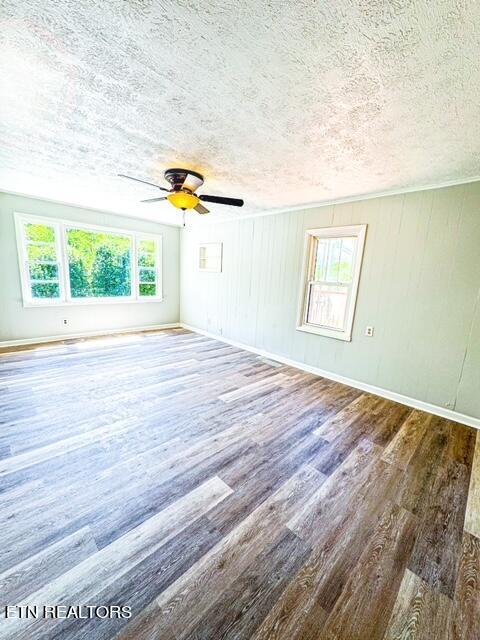 spare room featuring dark hardwood / wood-style floors, a wealth of natural light, ceiling fan, and a textured ceiling