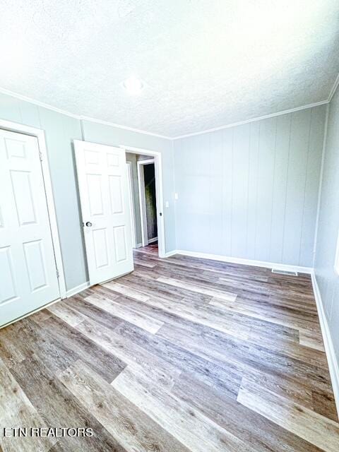 spare room featuring a textured ceiling, crown molding, and hardwood / wood-style flooring